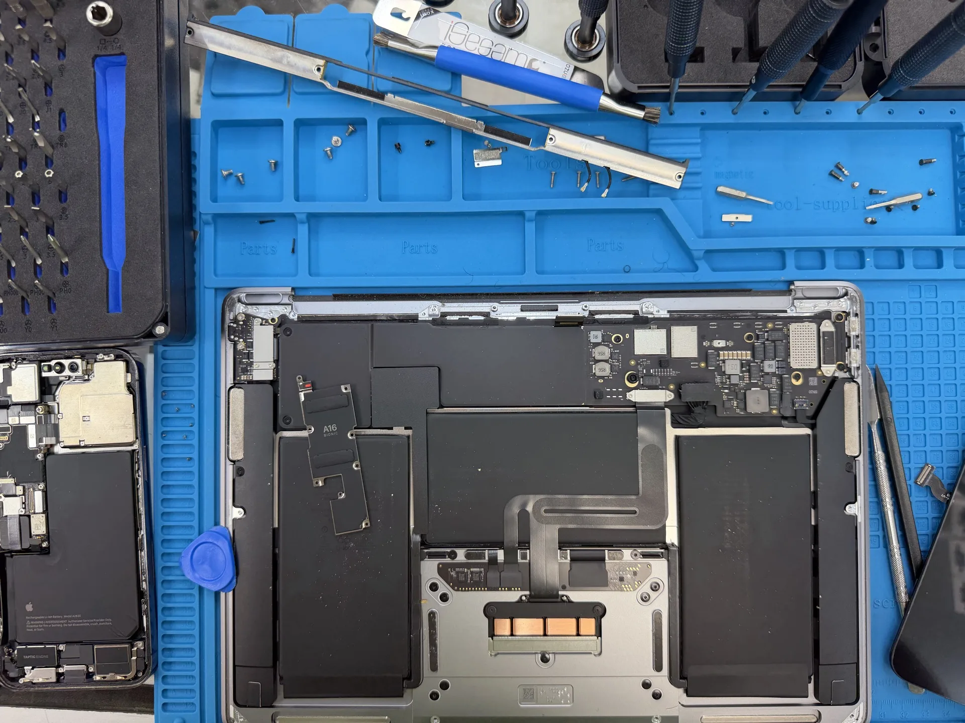 MacBook logic board and battery repair in progress on the workbench at Electronics Garden Repair NYC - near Penn Station